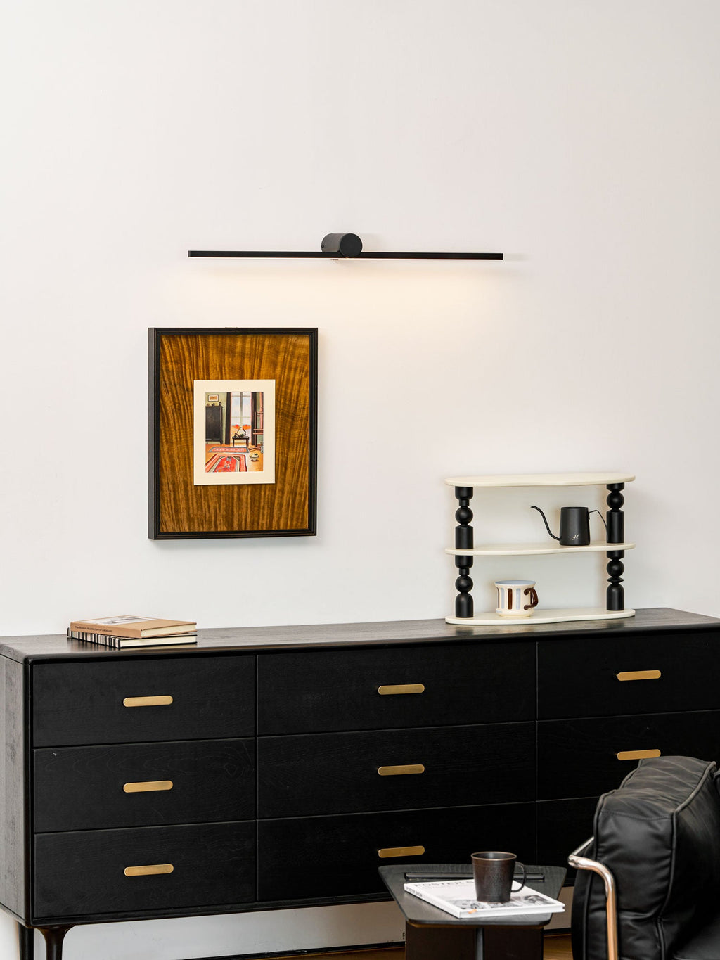 This Clérachic wall light glows above a bedroom dresser topped with books and a small ladder shelf.