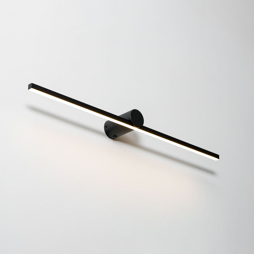 Angled studio shot of a lit Clérachic wall light, warm light spilling down a plain backdrop.