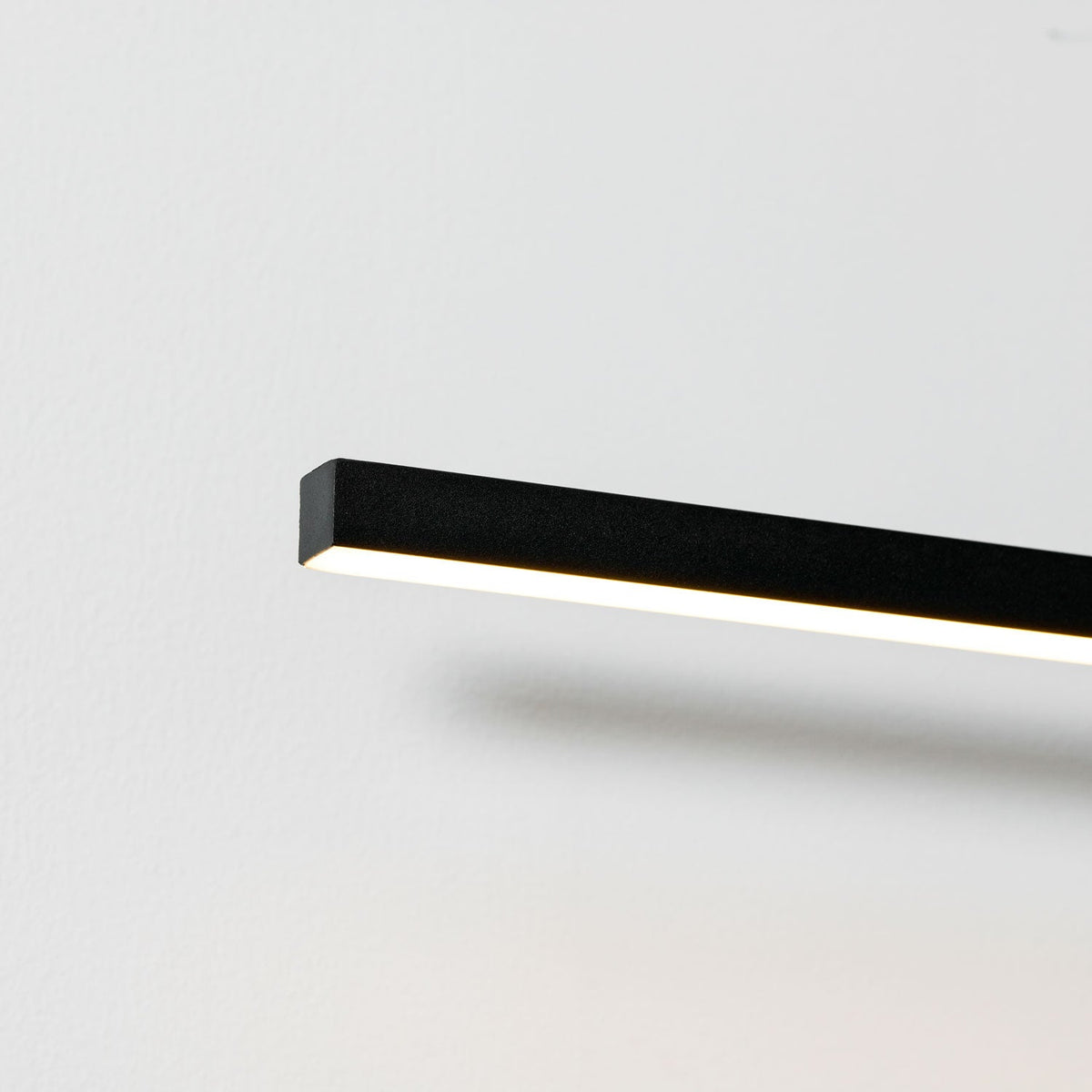 Close angled view of this Clérachic wall light's bar profile, its edge glowing warm.