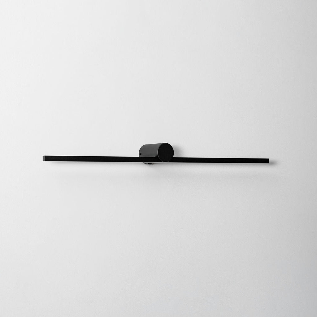 Close studio view of an unlit Clérachic wall light's round pivot mount and slim bar.