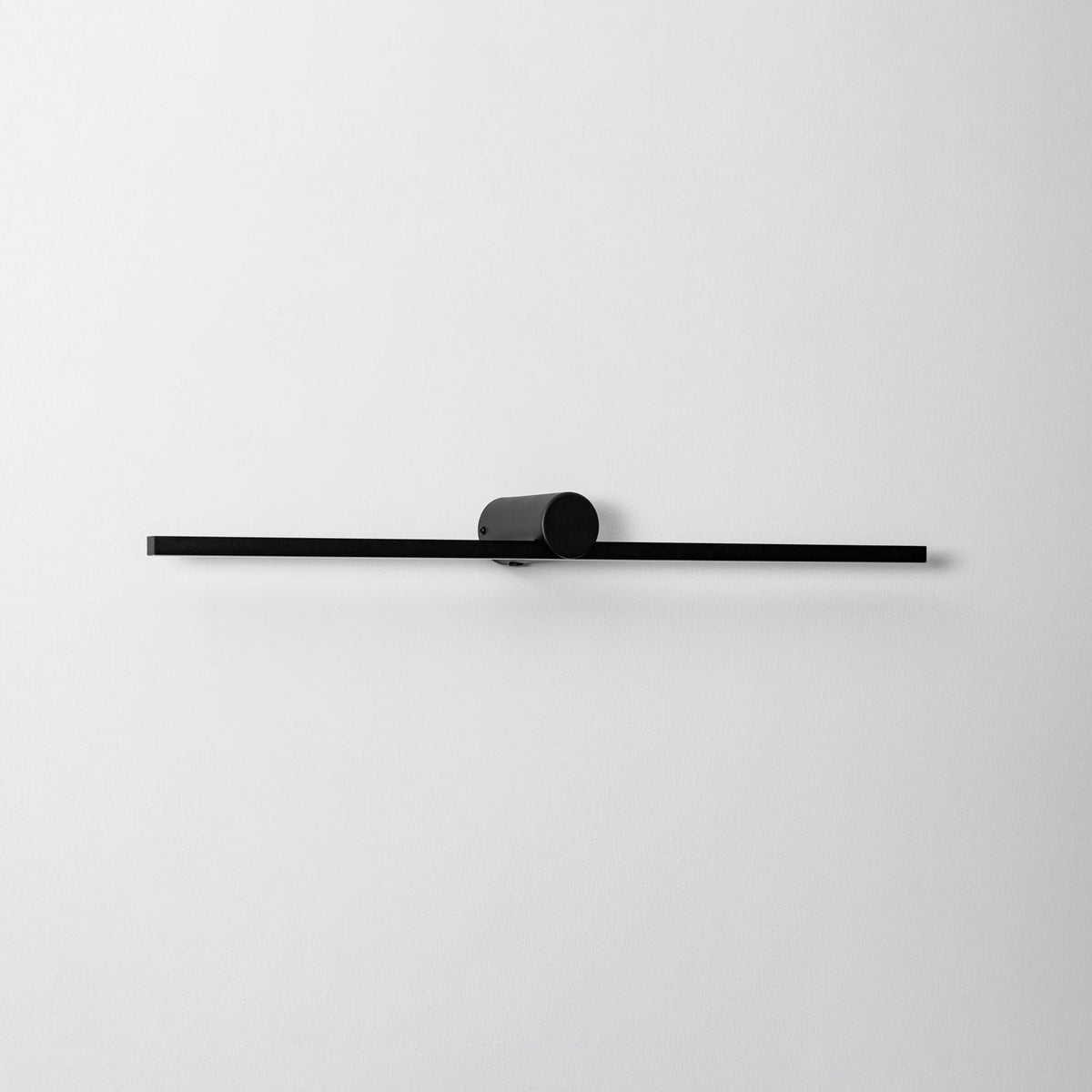 Close studio view of an unlit Clérachic wall light's round pivot mount and slim bar.