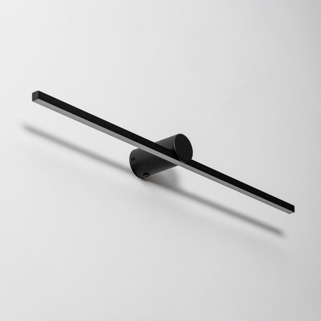 Angled studio view of a Clérachic wall light's round wall-mount bracket, unlit, with its fixing screw visible.