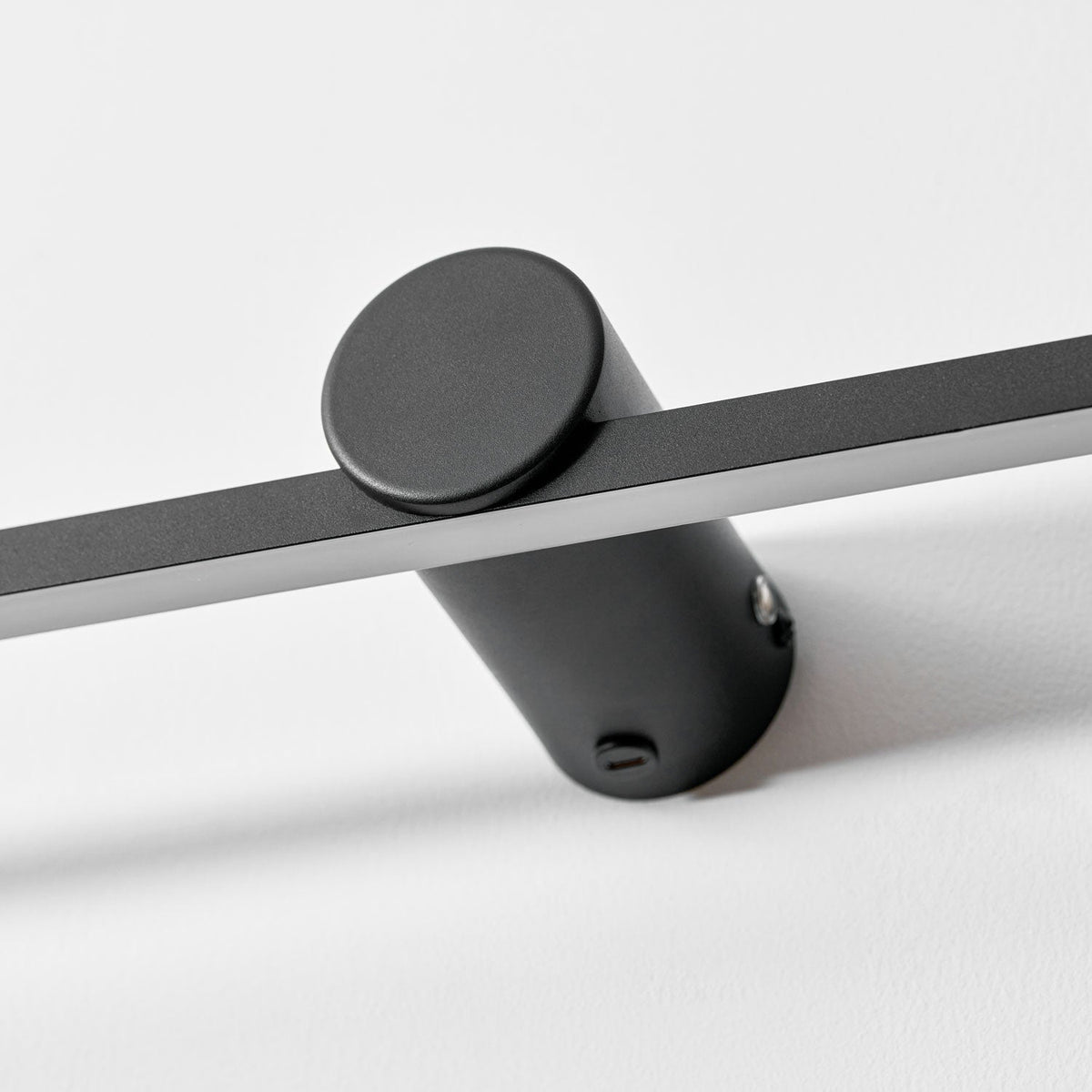 Extreme close view of this Clérachic wall light's round mount, showing its touch control and fixing screw.