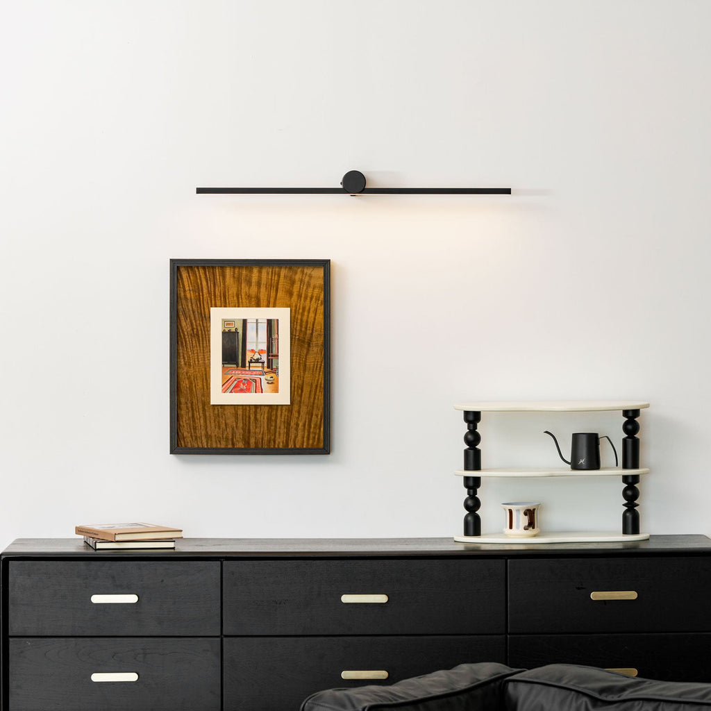 A Clérachic wall light sits unlit above a framed print, dresser, and ladder shelf with a kettle.