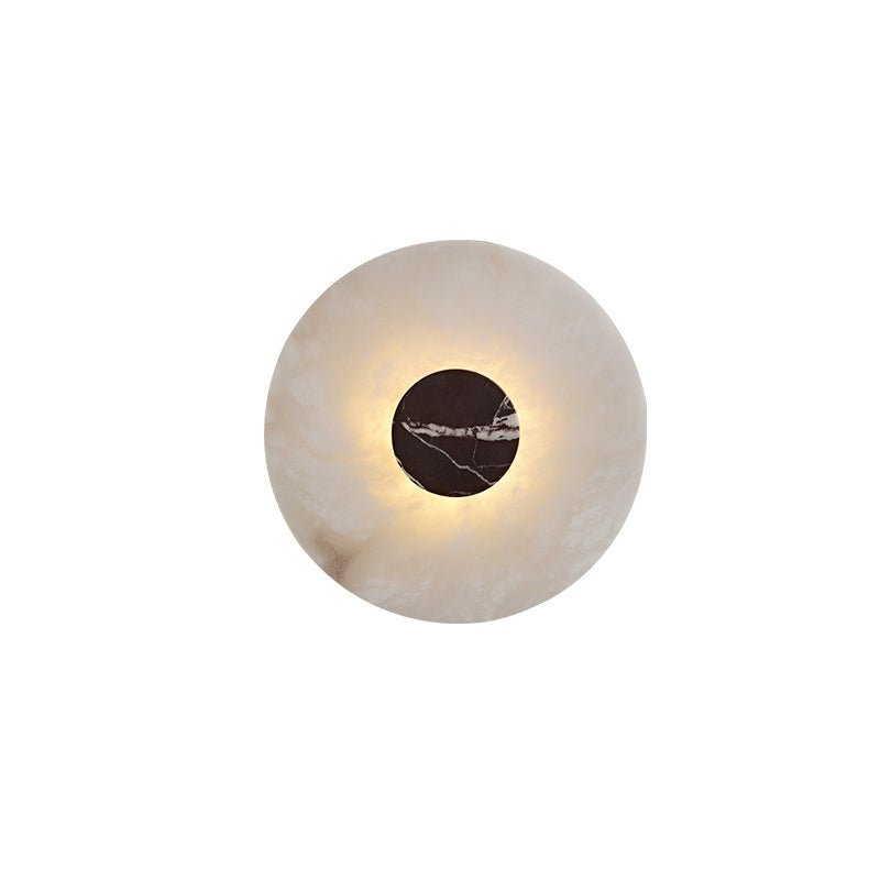 Close-up of a Clérachic alabaster wall light with a reddish-black marbled centre disc, its edge softly backlit.