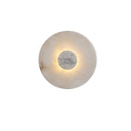 A soft warm halo rings the pale grey marble centre disc of this Clérachic alabaster wall light.