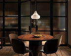 Eye-level view of the Tyler pendant lit over a round dining table, framed by a black-framed glass partition.