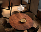 Tyler pendant lit above a round copper dining table, seen from above with velvet chairs and a brass bowl of nuts.