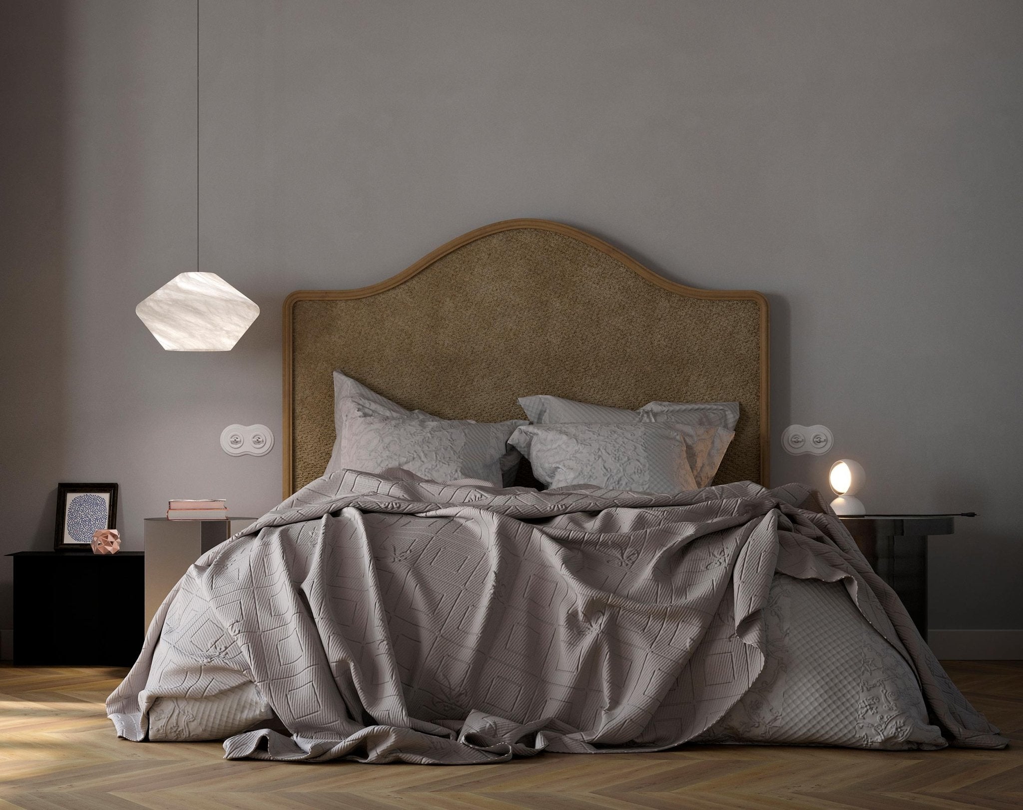 Tyler pendant hanging low beside a bed with an arched tan headboard, lit softly in a calm grey bedroom.