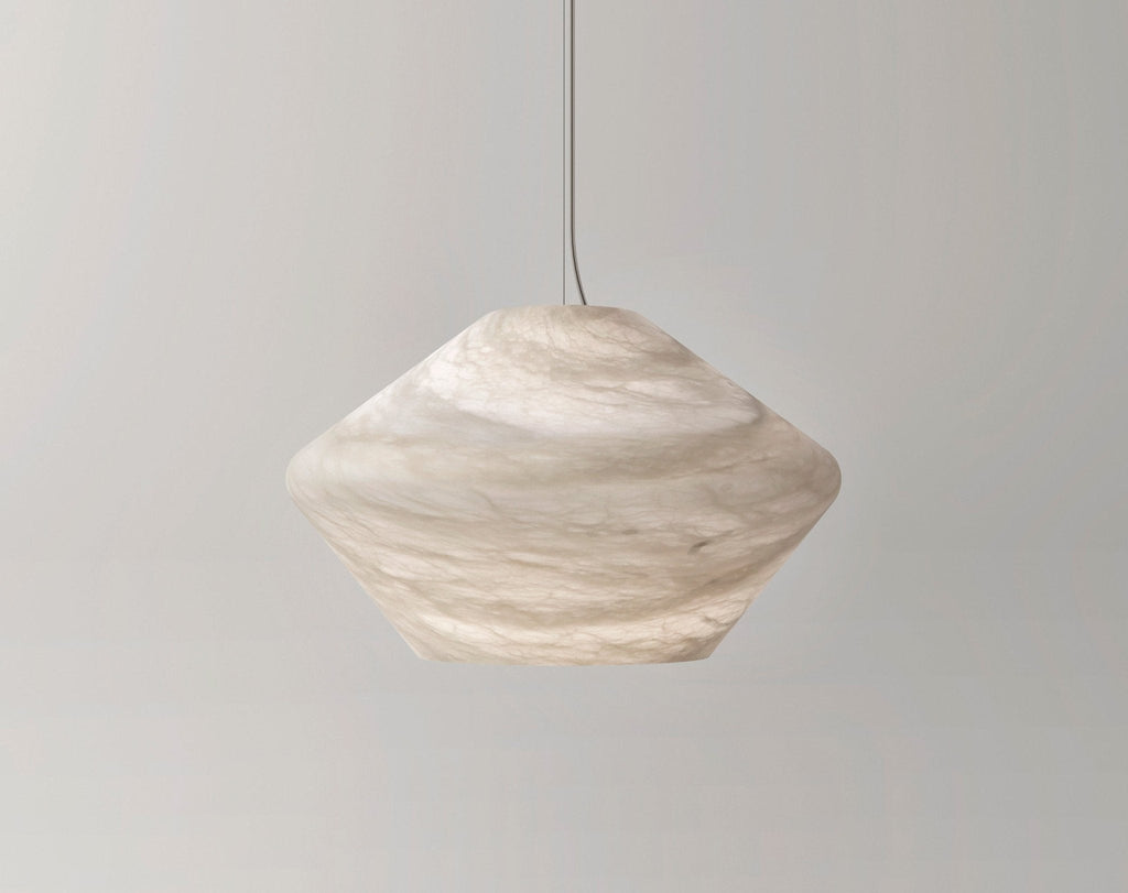 The Tyler pendant's faceted alabaster shade in a warm cream tone, hung against a pale grey wall and seen side-on.