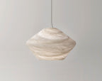 The Tyler pendant's faceted alabaster shade in a warm cream tone, hung against a pale grey wall and seen side-on.