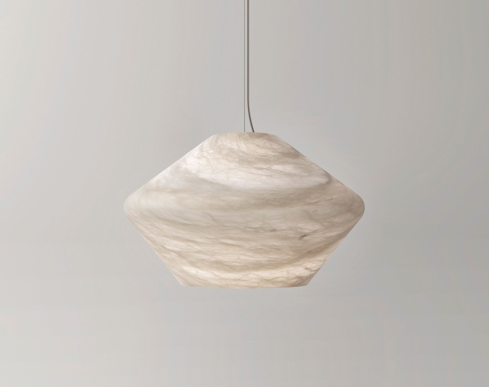 The Tyler pendant's faceted alabaster shade in a warm cream tone, hung against a pale grey wall and seen side-on.
