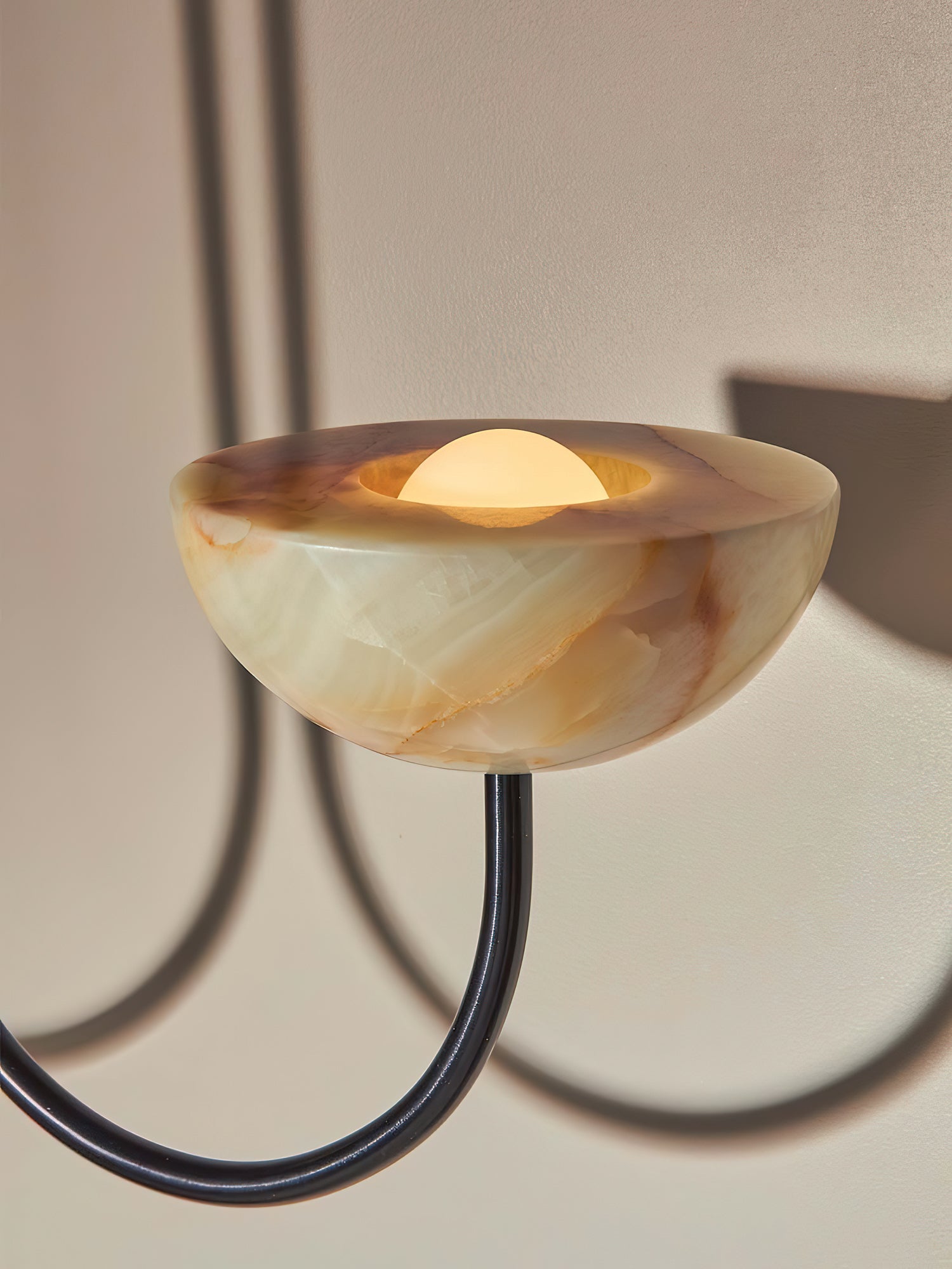 Clérachic close-up of a jade stone bowl with the frosted bulb glowing at its centre on the black arm.