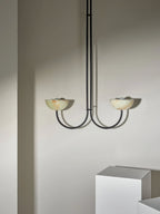 Clérachic black-finish Lunaris pendant with jade bowls hanging against the plaster wall of a bare styled room.