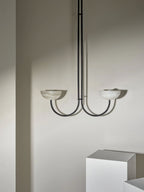 Clérachic black Lunaris pendant with alabaster bowls, its twin arms throwing soft shadows across the plaster wall.
