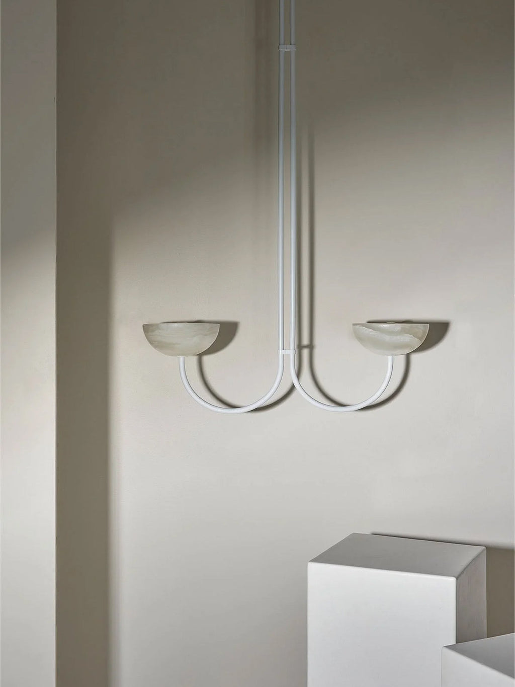 Clérachic white Lunaris pendant with pale stone bowls, hung in a corner where daylight grades across the wall.