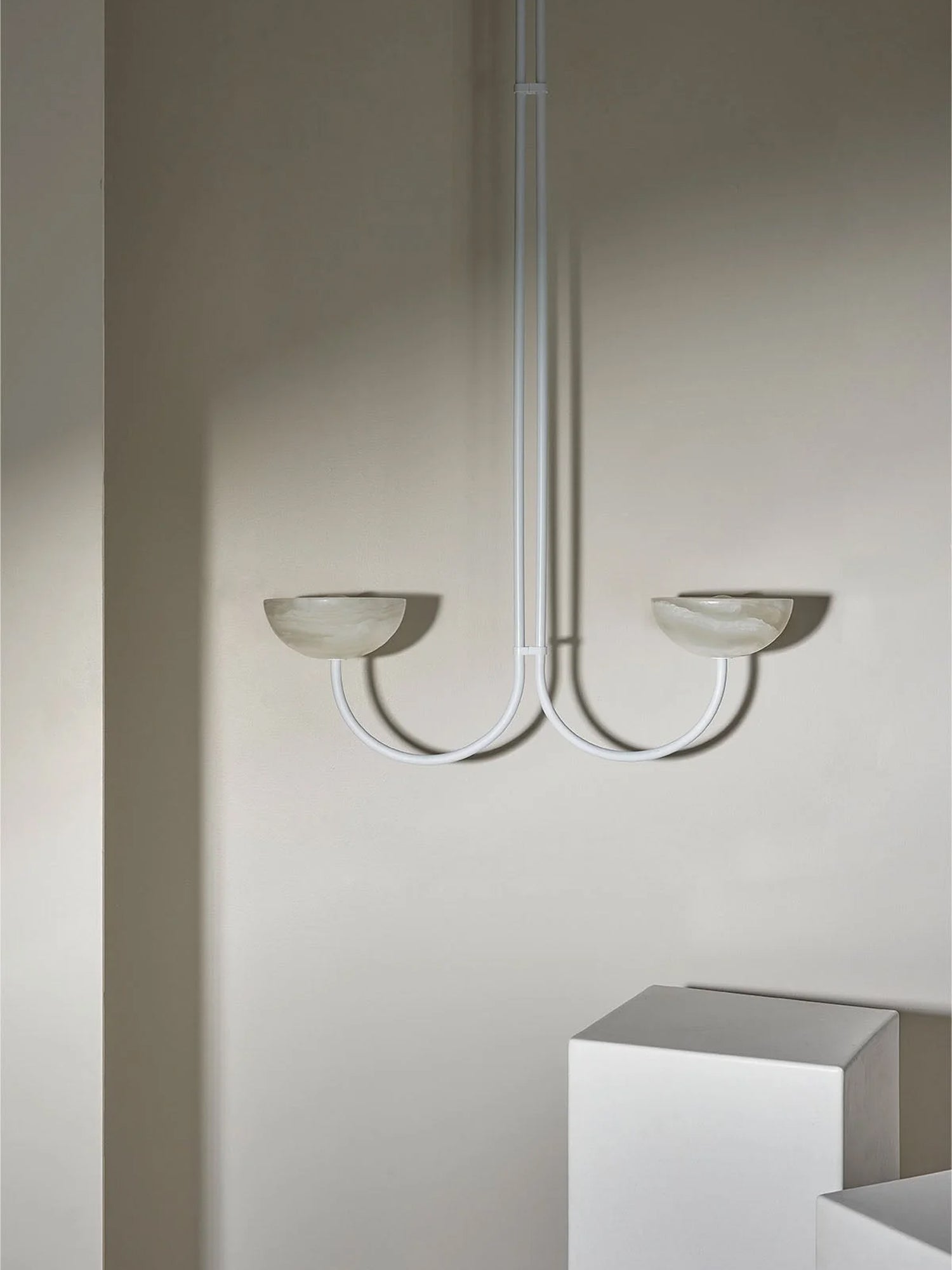 Clérachic white Lunaris pendant with pale stone bowls, hung in a corner where daylight grades across the wall.
