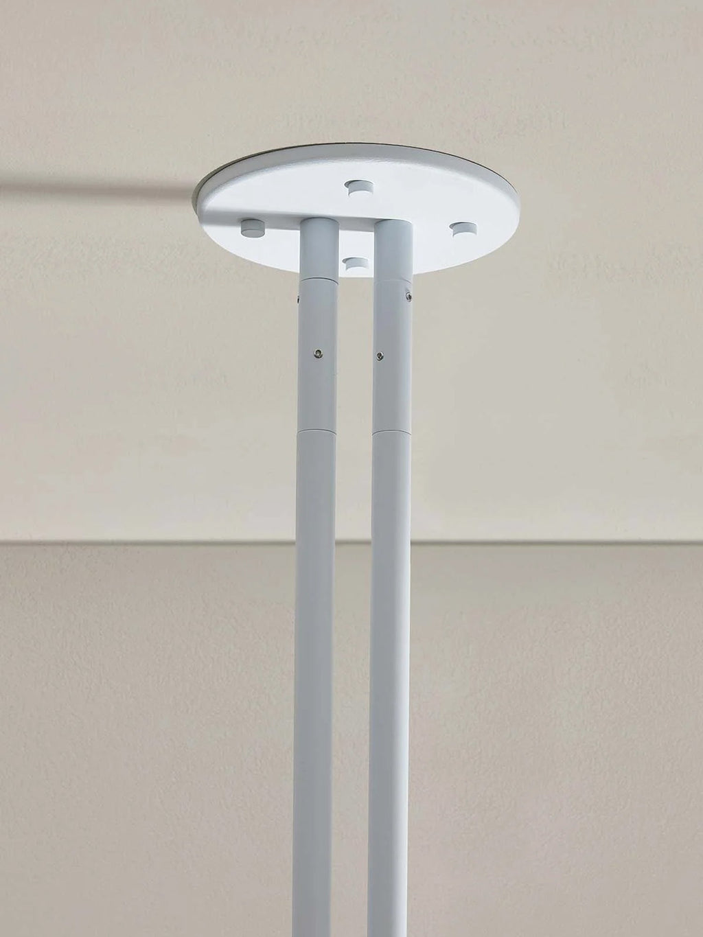 Detail of the Clérachic round white ceiling plate where the two support rods meet, screw fixings visible.