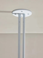 Detail of the Clérachic round white ceiling plate where the two support rods meet, screw fixings visible.