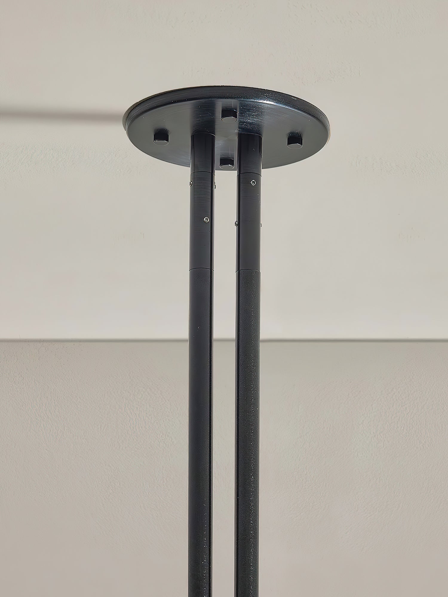Detail of the Clérachic black ceiling canopy and its pair of support rods fixed at the mounting plate.