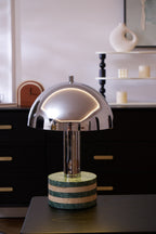 Close crop of the lit Clérachic lamp against the dark dresser scene, dome and marble base filling most of the frame.