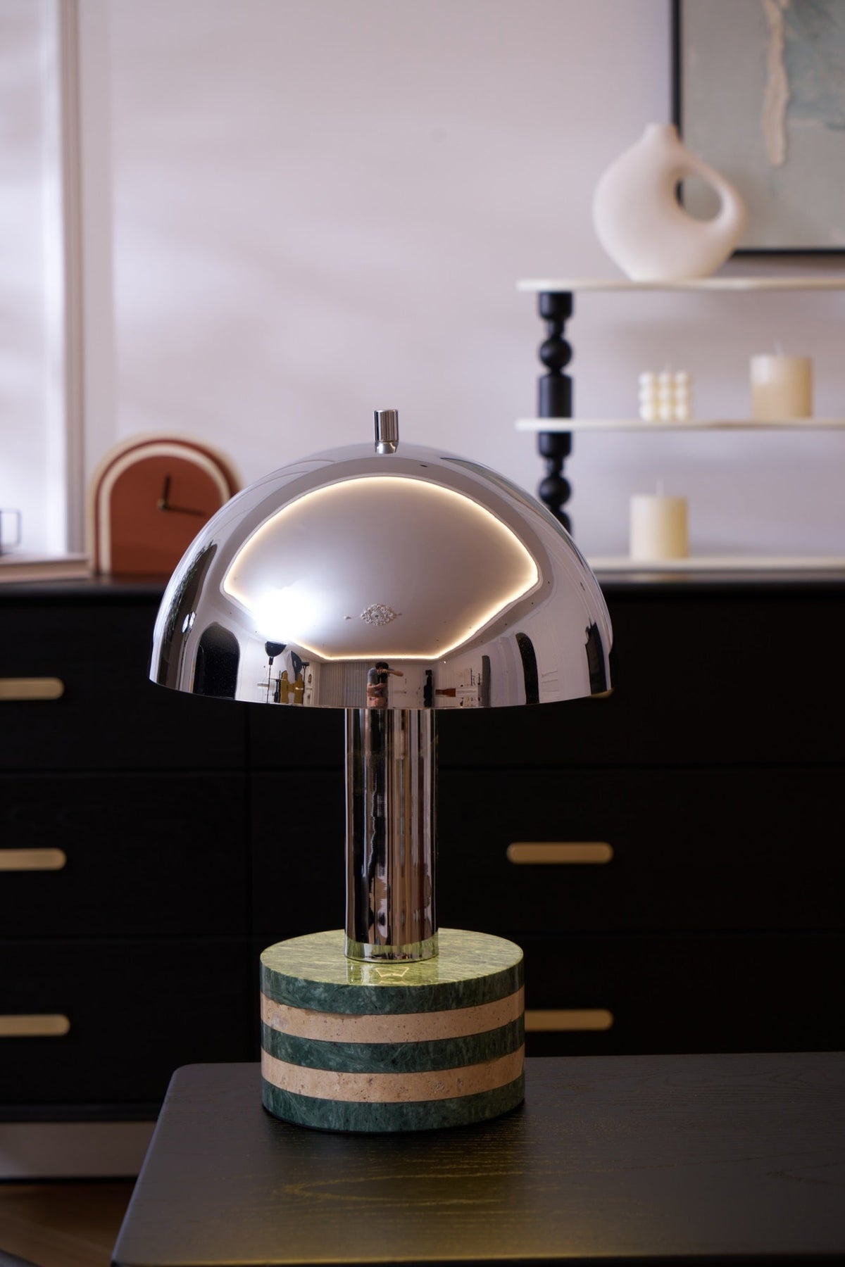 Close crop of the lit Clérachic lamp against the dark dresser scene, dome and marble base filling most of the frame.