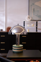 Portrait crop of the Clérachic lamp on the dresser, the tall turned-wood shelf and candles rising behind it.