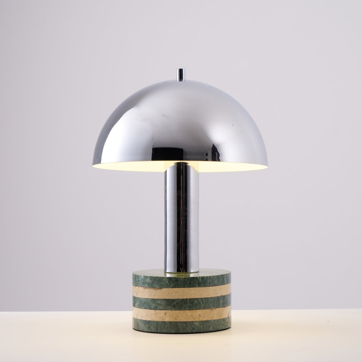 Studio shot of the Clérachic lamp against a plain grey backdrop, dome and striped marble base shown straight-on.