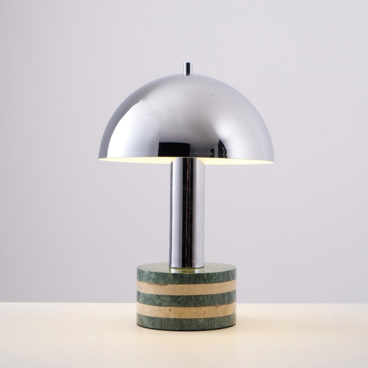 Clérachic lamp on a grey backdrop at a slight angle, a soft shadow falling from its marble base onto the surface.