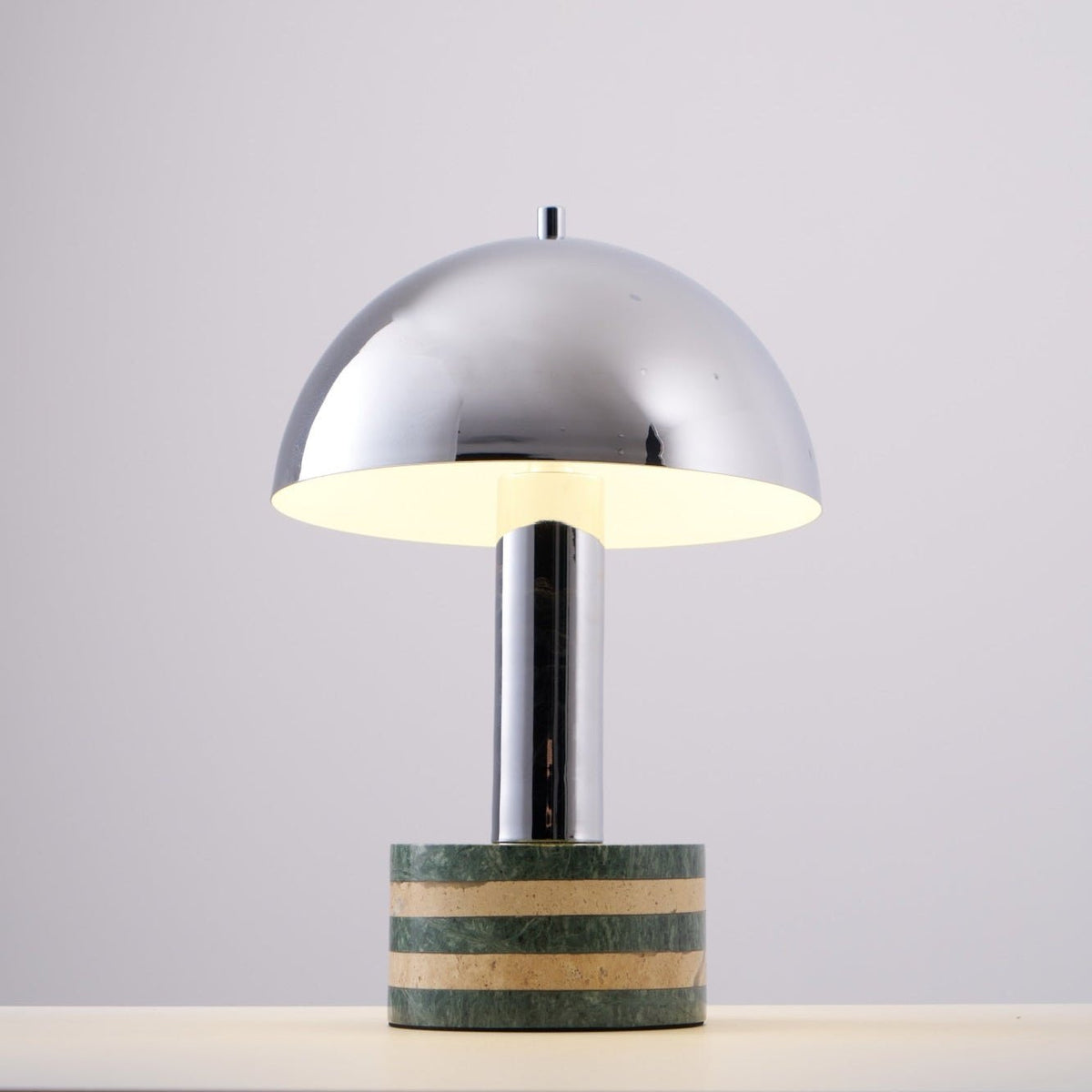 Clérachic lamp photographed at an angle with its dome lit from within, a warm glow visible along the inner rim.