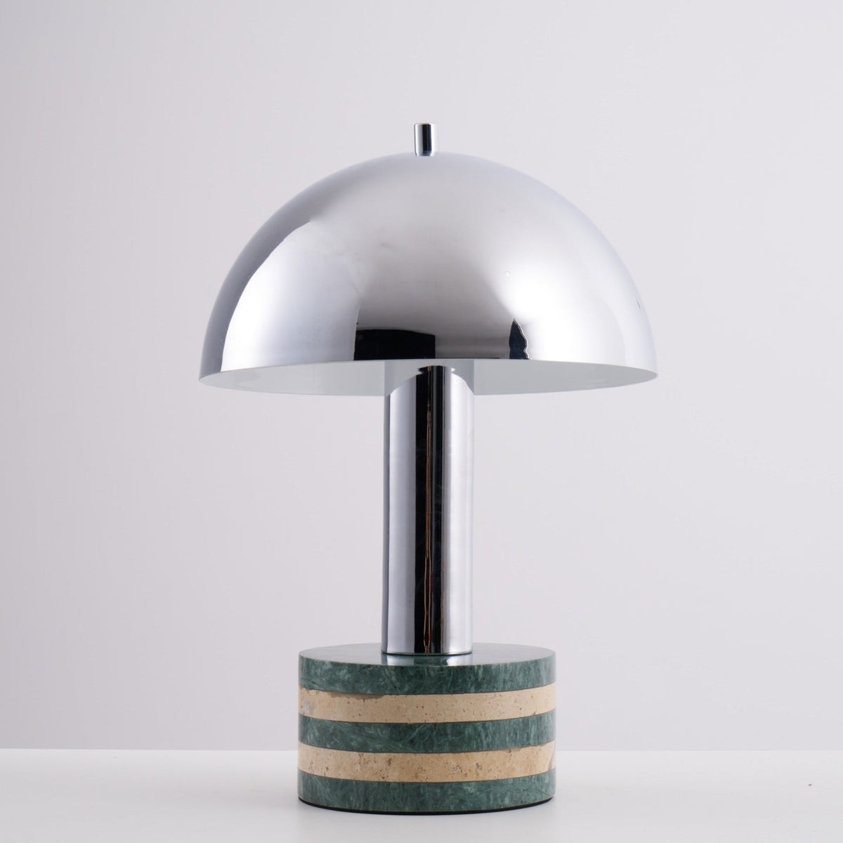 Clérachic lamp angled slightly on the grey backdrop, the striped marble base catching the studio light.