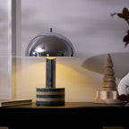 Clérachic lamp lit beside a stacked wooden ring ornament instead of the books, same dark cabinet and warm glow.
