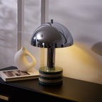 Tighter vertical crop centred on the lit Clérachic lamp, the ceramic vase and an open book close against its base.