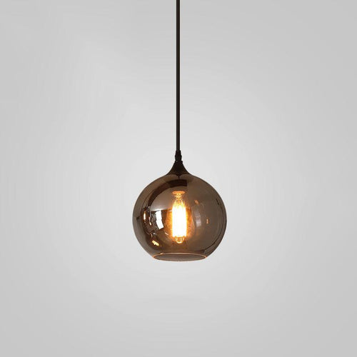 Hand-blown smoke gray glass pendant glowing warmly over a table