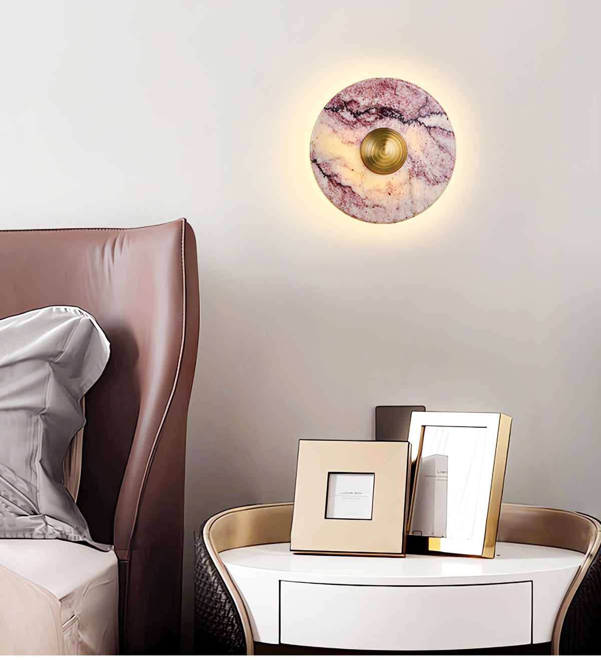 A lit Clérachic purple marble wall light hangs above a brown leather headboard, beside a round nightstand and framed photos.