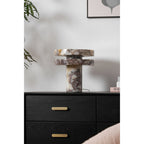 Clérachic lamp unlit on the dresser, a dark branch overhead and the drawer pulls lined up below its marble base.