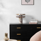 Wider view of the unlit Clérachic lamp on the dresser, a small ceramic vase and blush pouf visible in the foreground.