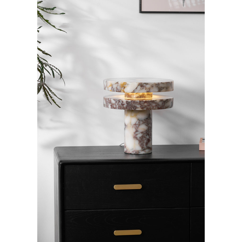 Clérachic lamp lit on the dresser with a branch reaching in from the right, books stacked just behind its base.