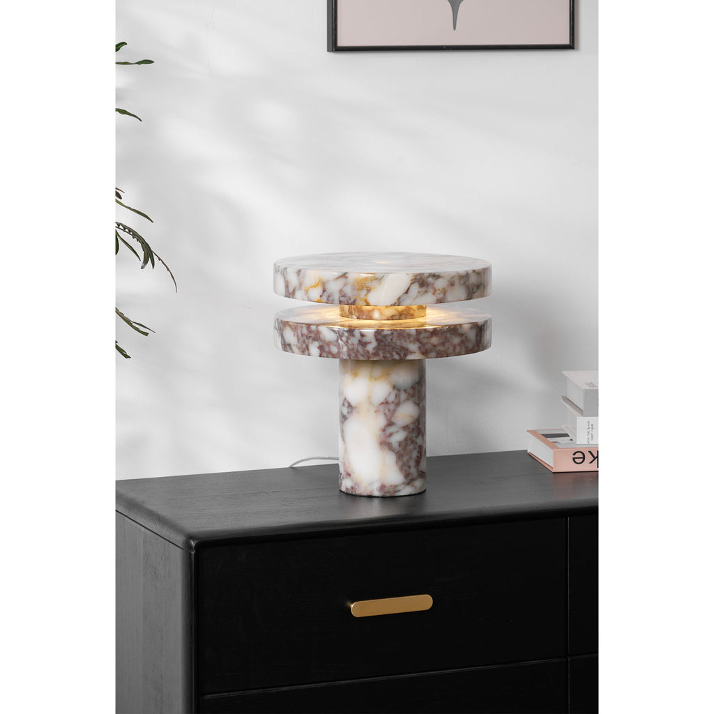Clérachic lamp lit on the dresser beneath a corner of framed pink art, the eucalyptus branch and book stack framing it.