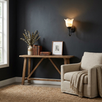 Against a deep navy wall, this matte black Clérachic wall sconce glows above a console styled with books and a vase.