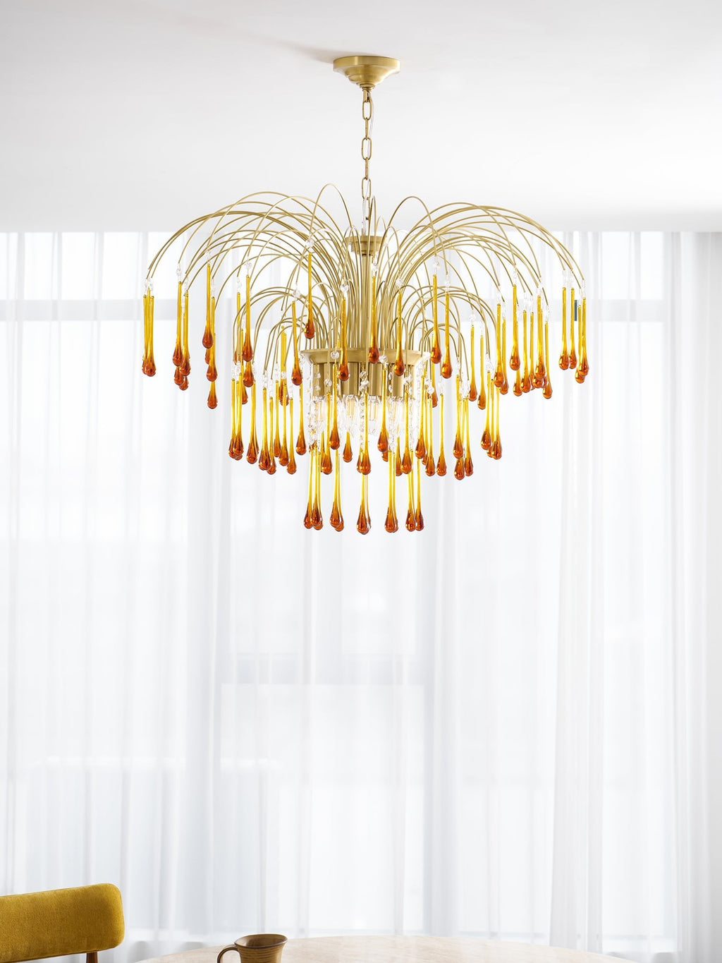 Bright window light falls across this Clérachic pendant's caramel crystal drops beside a sheer curtain.