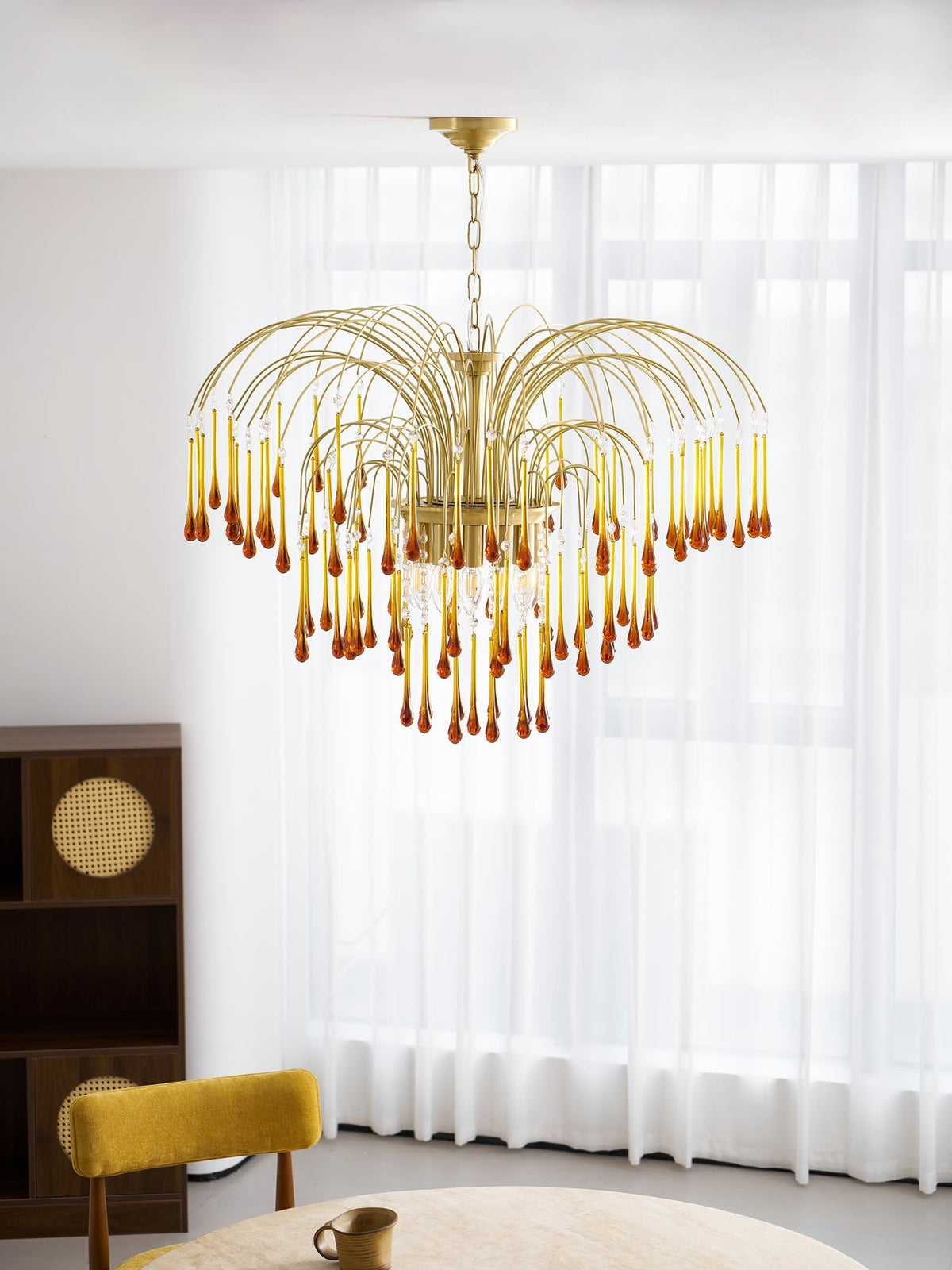 This Clérachic pendant hangs above a round table set with a mug, near a cane-panelled bookshelf.