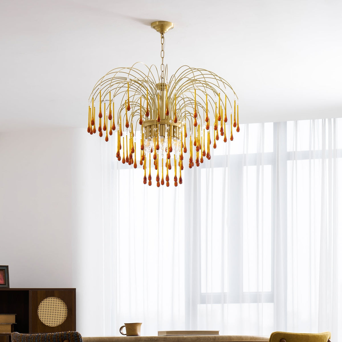 Caramel crystal drops on this Clérachic pendant catch the light beside a mustard-yellow chair and dark wood shelving.
