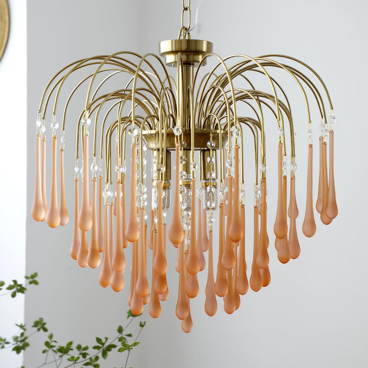 A softer blush-caramel tone shows on this Clérachic chandelier's crystal drops, spread wide in a fountain shape on a plain background.