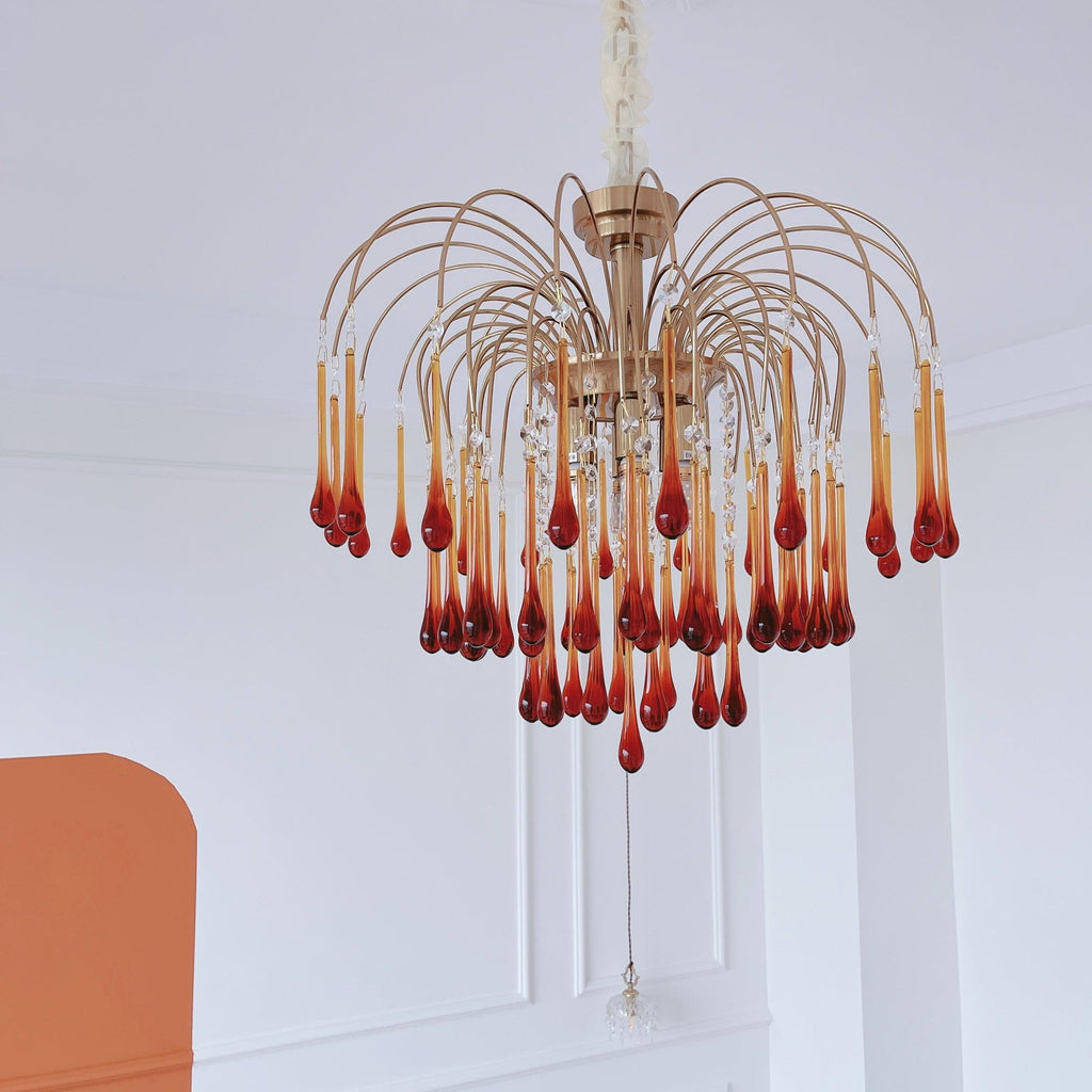 A single crystal drop hangs below this Clérachic chandelier, its caramel tiers set against a terracotta wall panel.