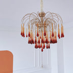 A single crystal drop hangs below this Clérachic chandelier, its caramel tiers set against a terracotta wall panel.