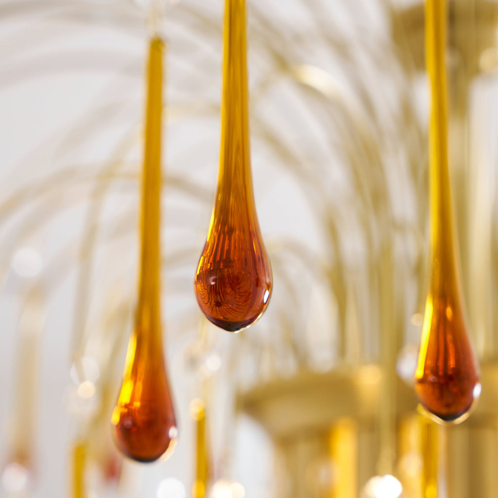 Close view of caramel crystal drops on this Clérachic chandelier, more drops and brass arms blurred in the background.