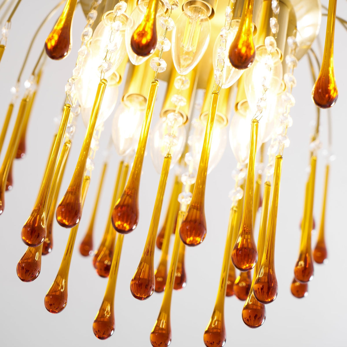 Close view of caramel crystal drops clustered around the lit bulbs at the centre of this Clérachic chandelier.