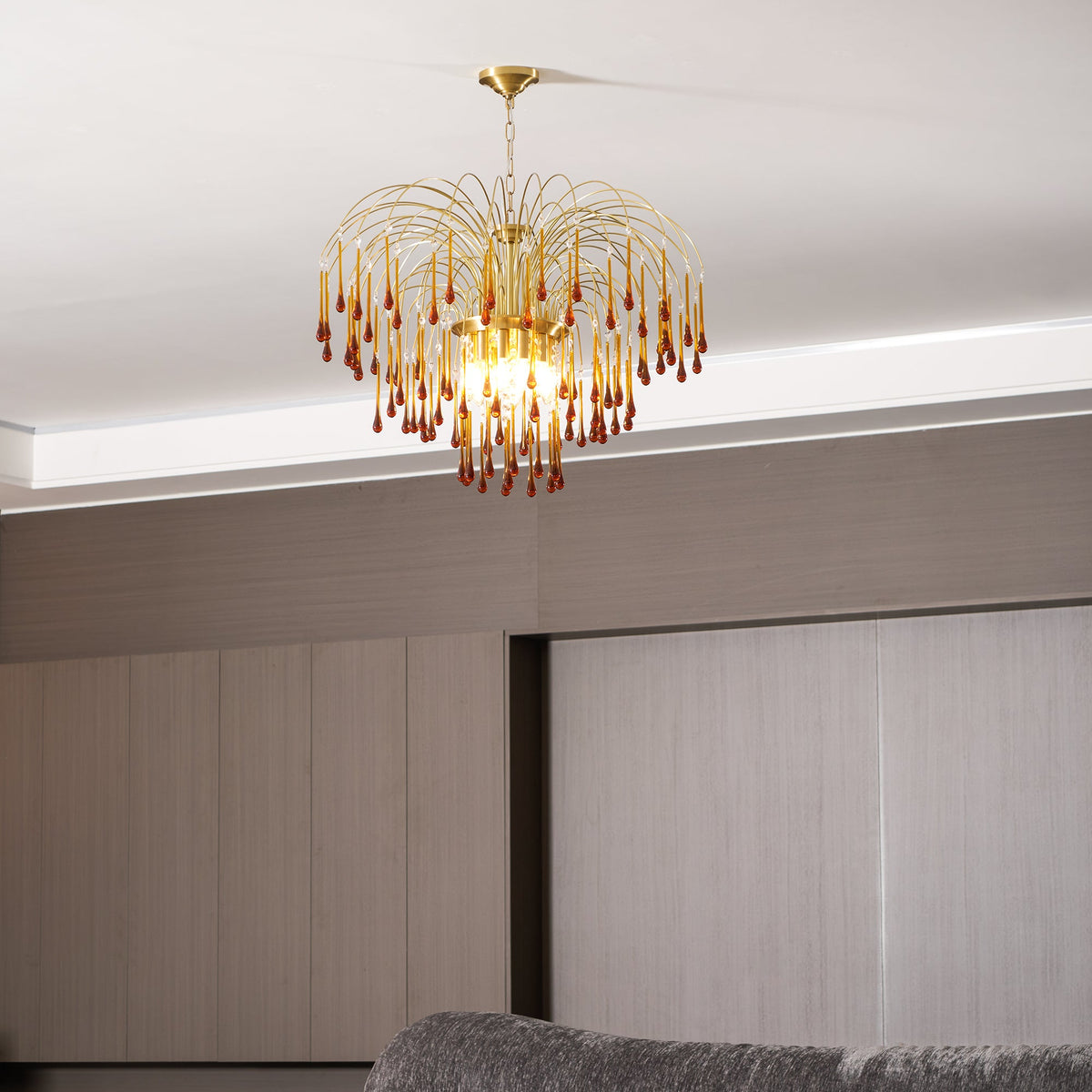 A closer view of this Clérachic pendant shows its lit caramel crystal drops against ceiling trim and pale panelling.