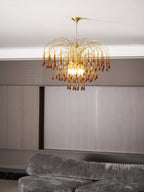 This Clérachic pendant's caramel crystal drops hang above a grey sofa in daylight, pale wood panelling behind.